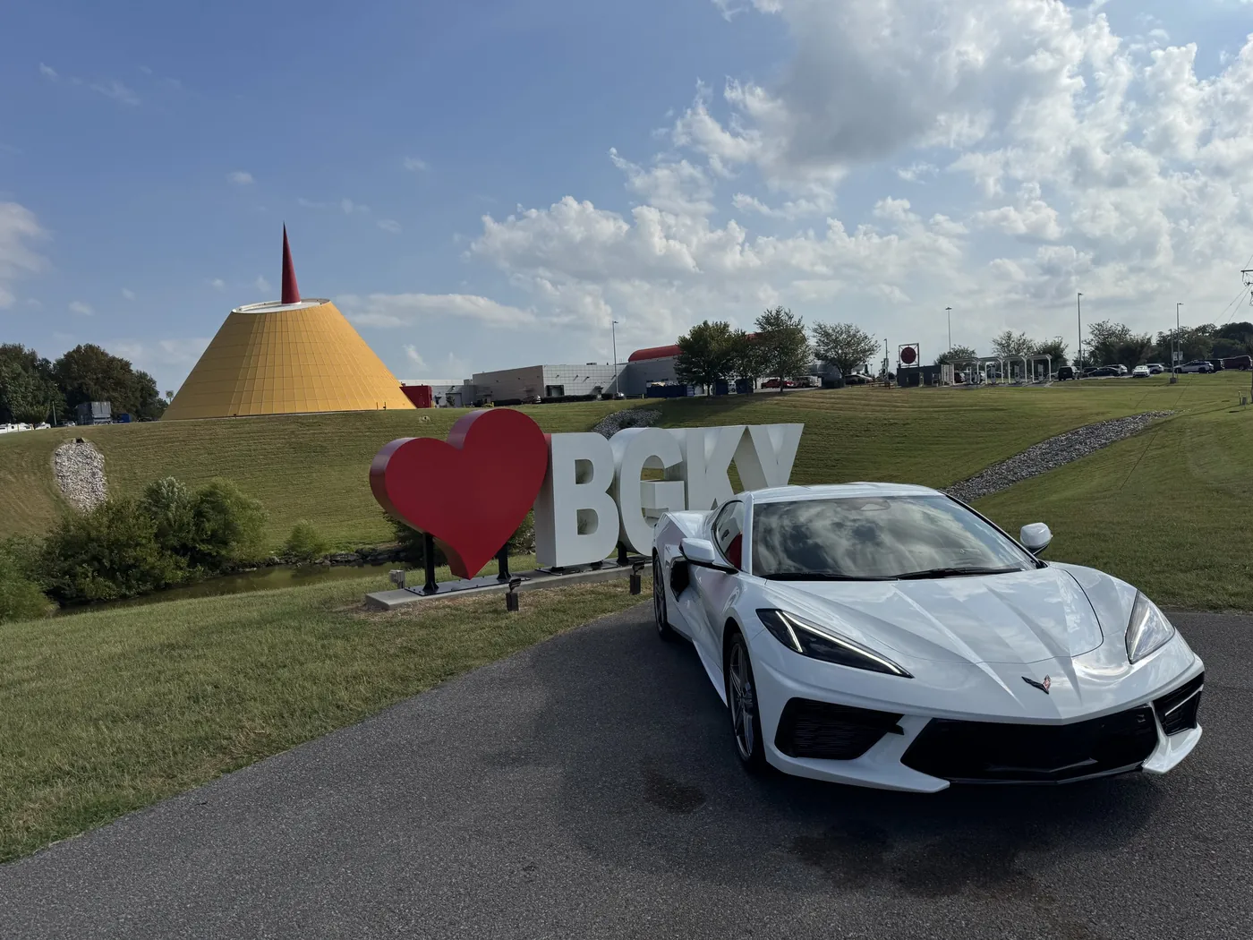 A white Corvette Stingray beside the BGKY sign at the National Corvette Museum
