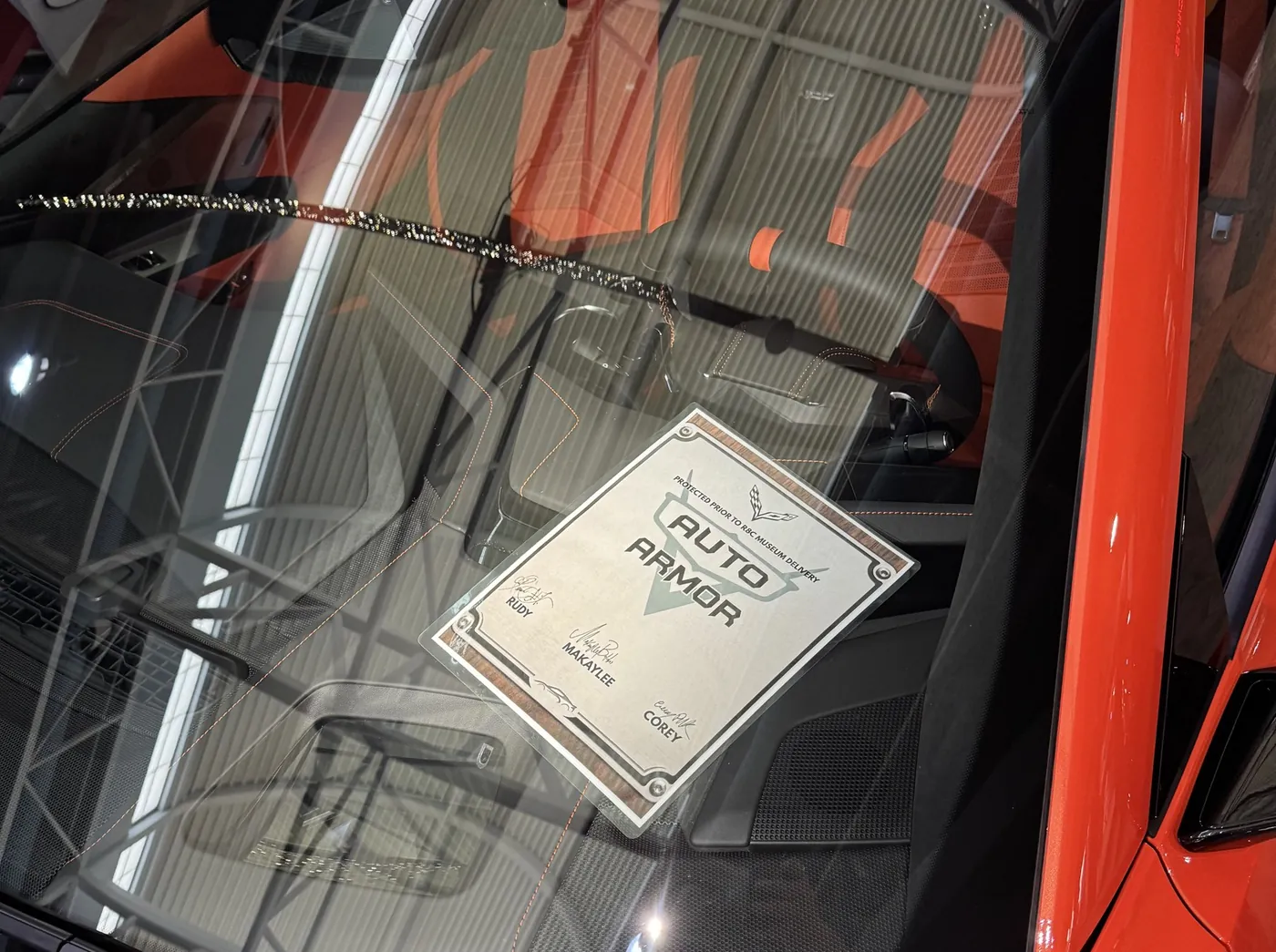 Windshield of a red Corvette with the Auto Armor card on the dash